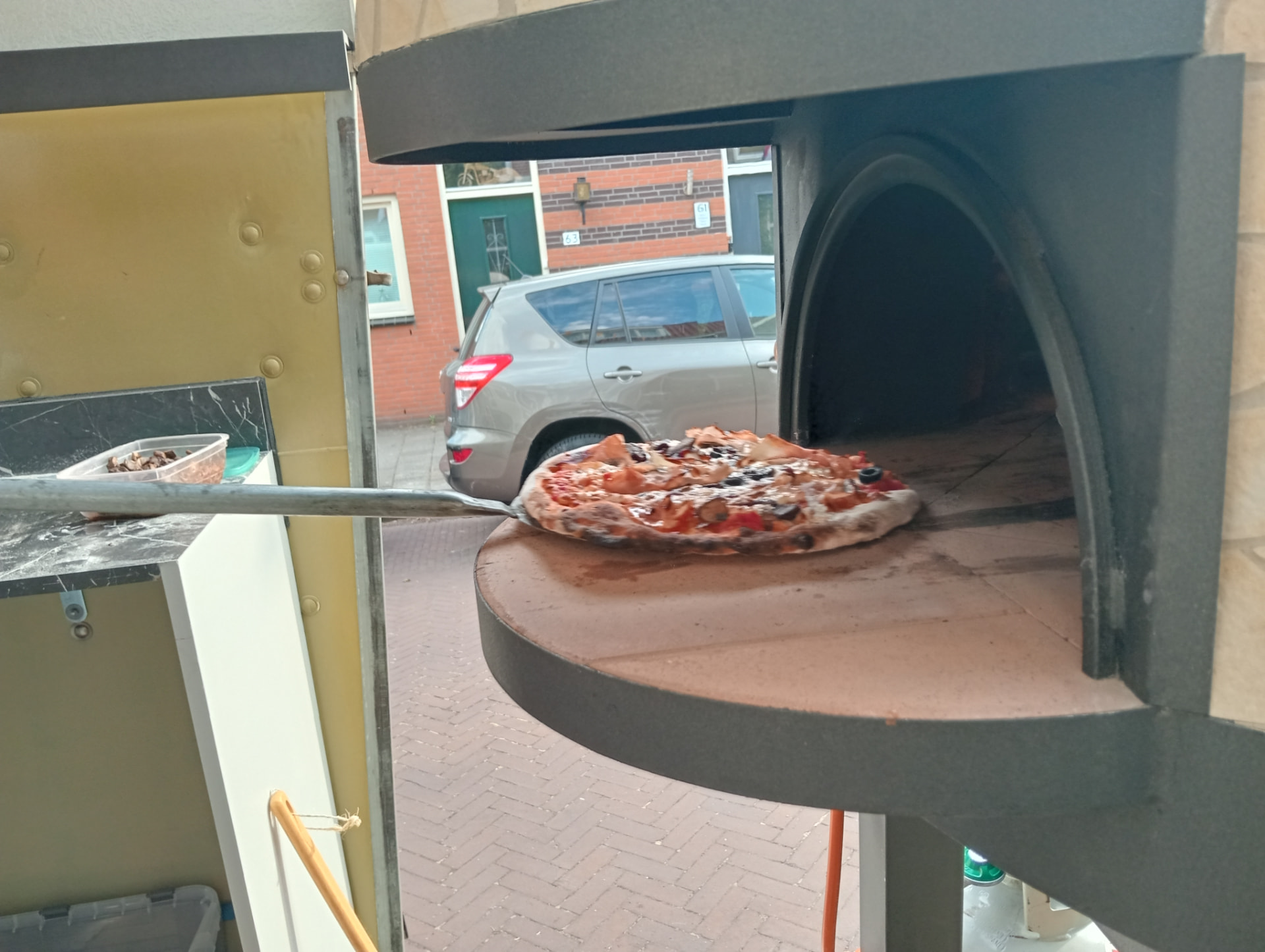 Pizza die met de schep uit de houtoven wordt gehaald