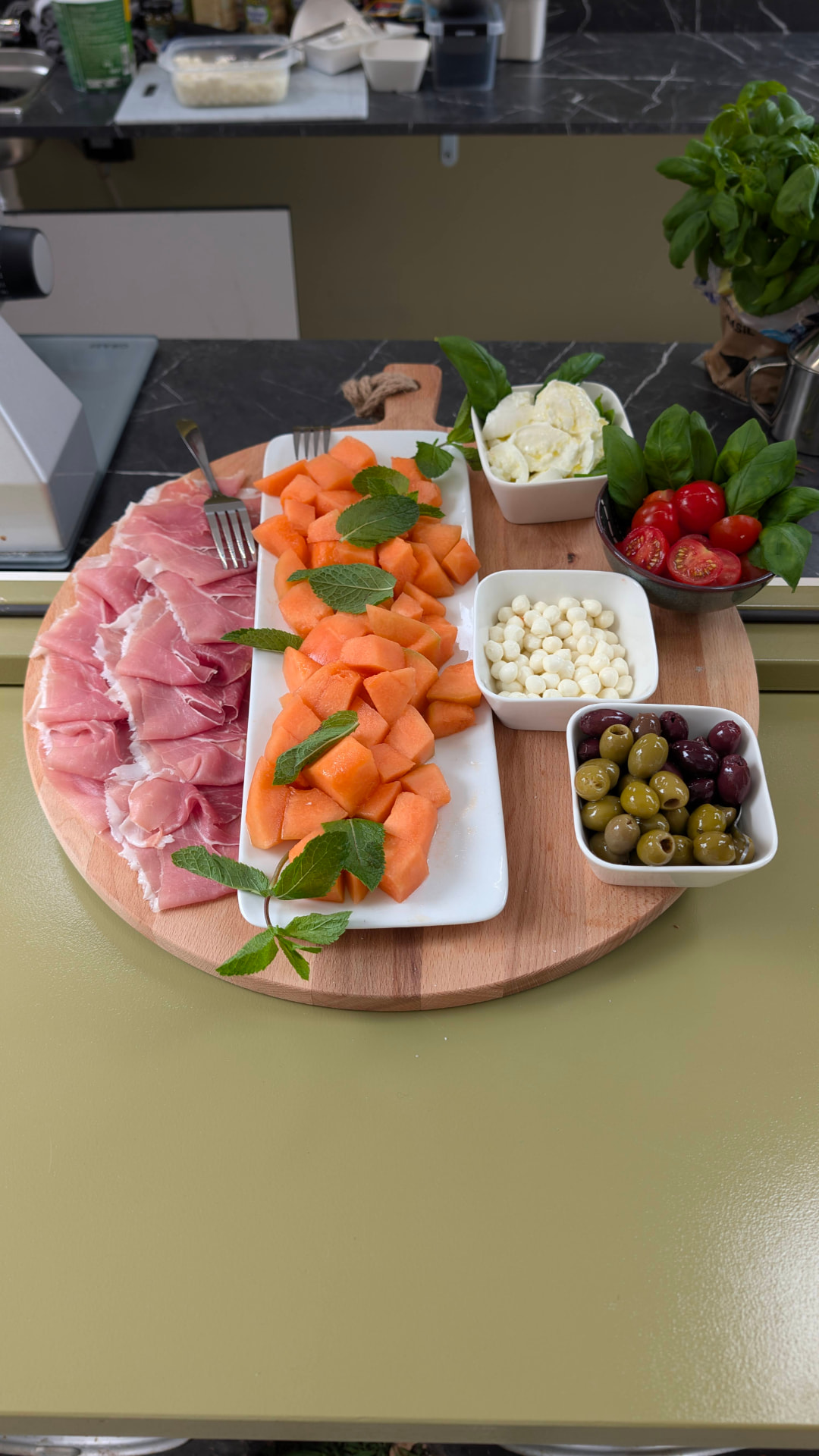 Antipastiplank met ham, meloen, mozzarella, tomaatjes en olijven