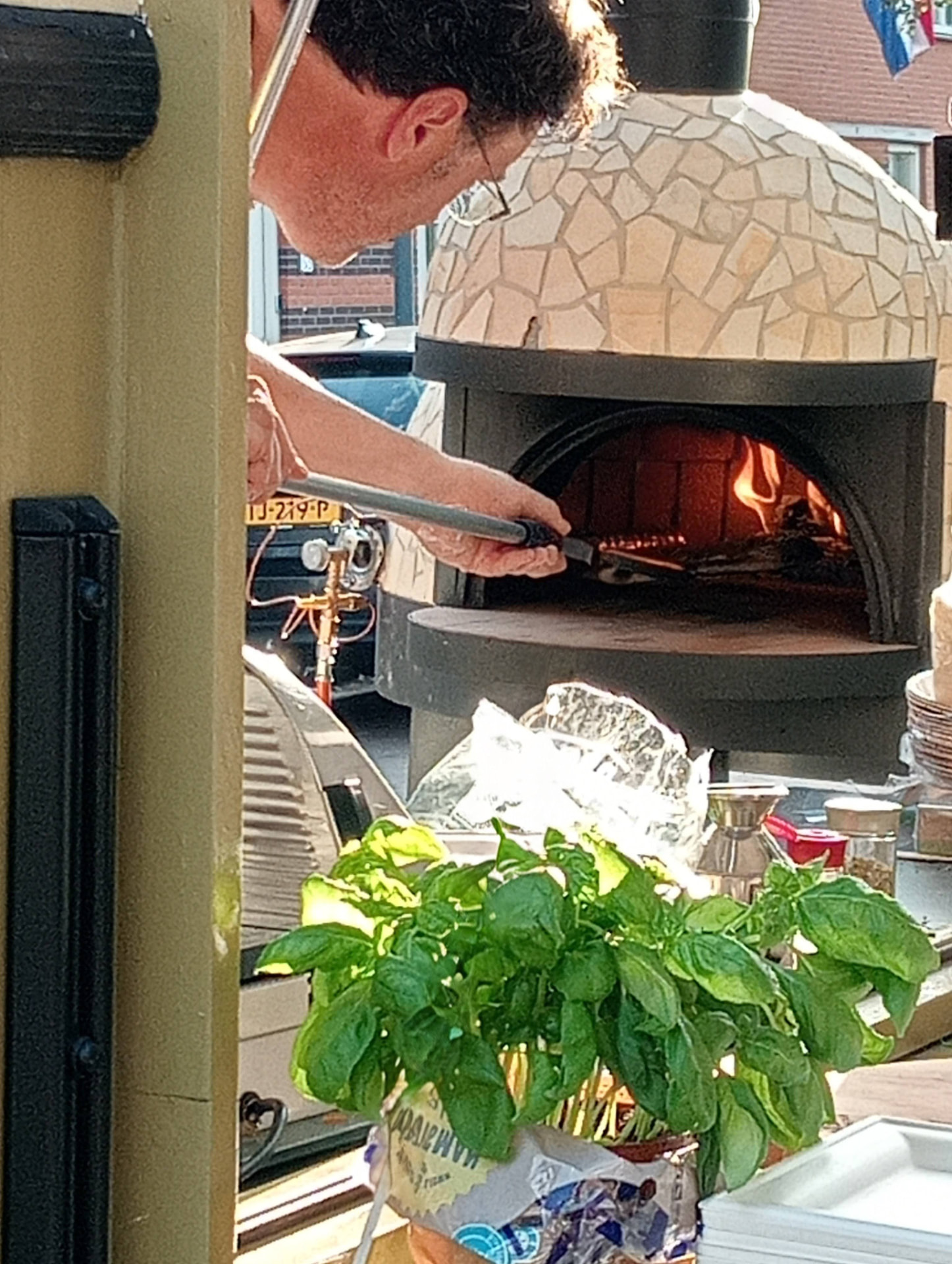 Frans stookt het vuur op in de houtoven van de pizzatrailer