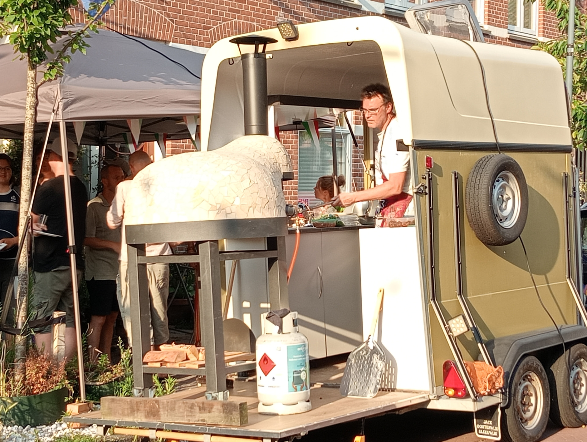 De pizzatrailer met houtoven op straat tijdens een buurtfeest