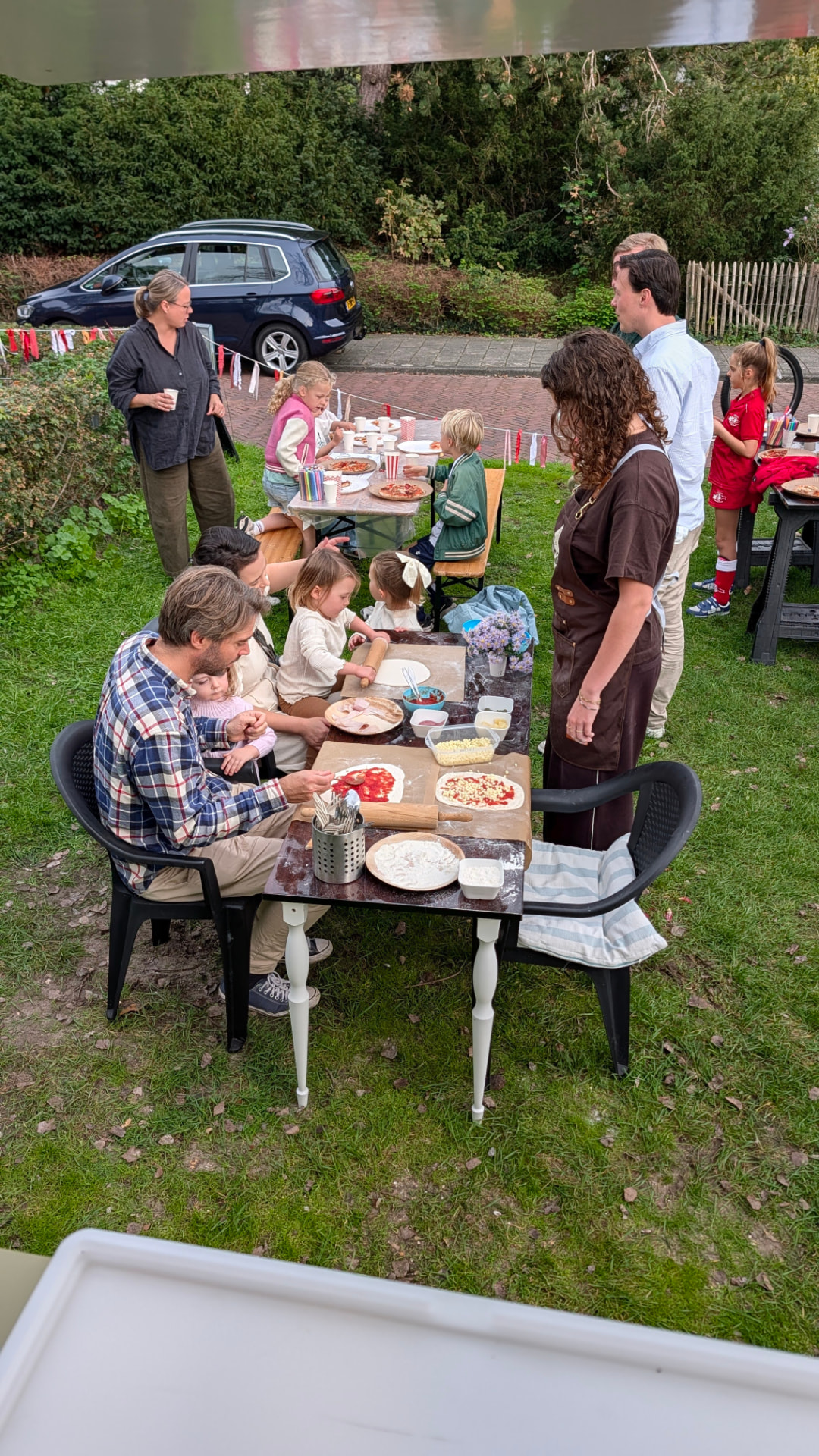 Gasten maken en eten pizza's aan een tafel in de tuin tijdens het event in Bentveld